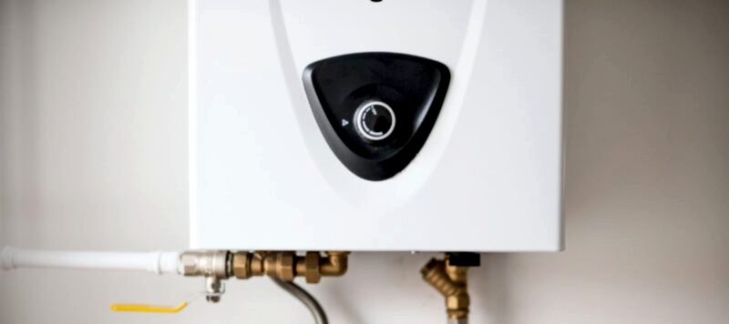 close up of black control knob on white tankless water heater installed in a houston home