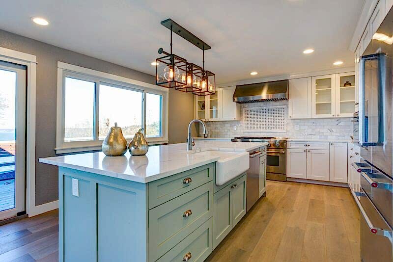 kitchen with minty blue/green cabinets, an island with a sink and dishwasher