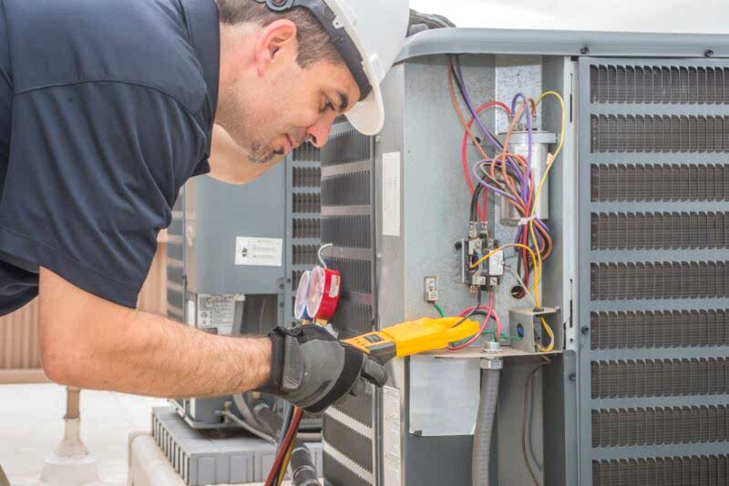 friendly air tech ac technician repairing air conditioner installed outside a home
